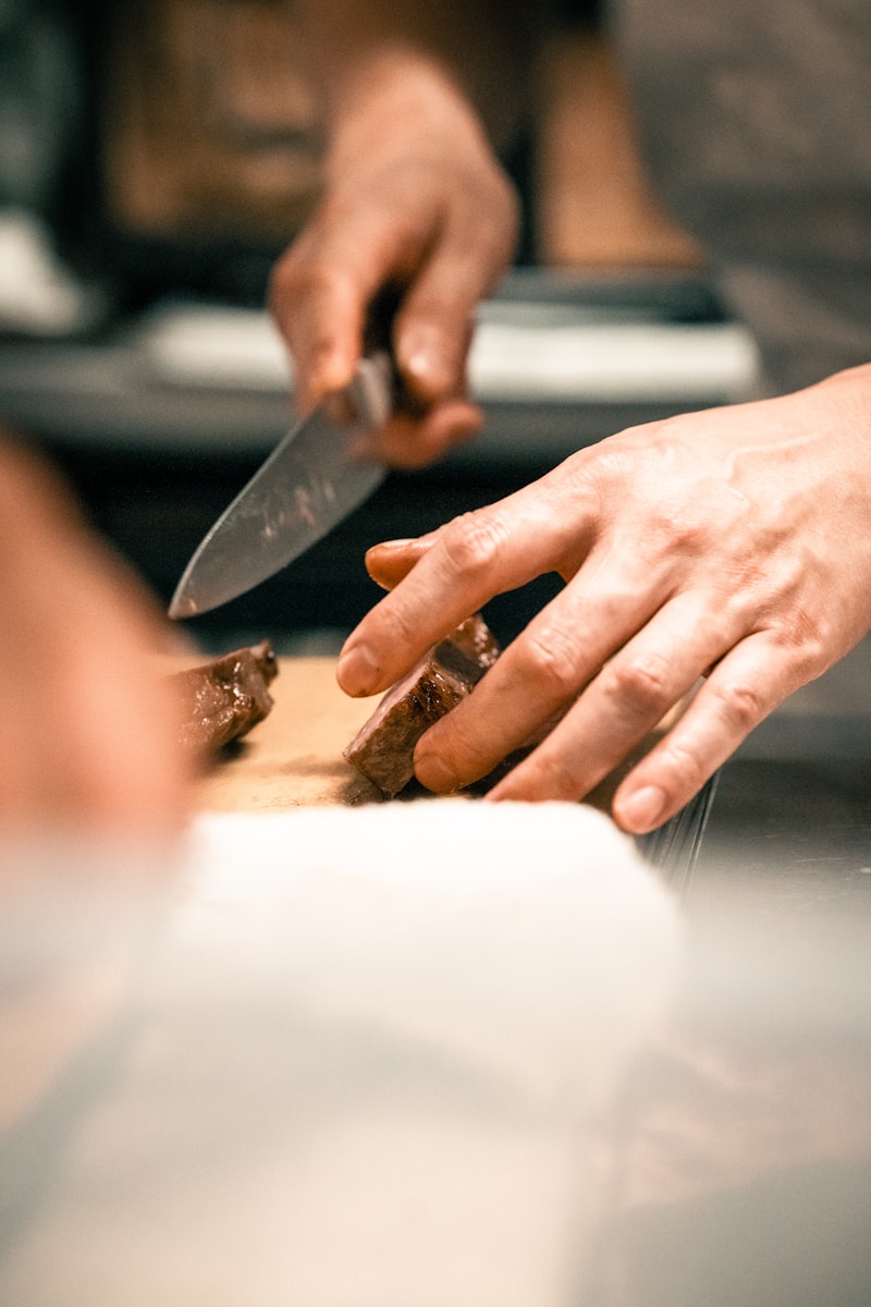a person cutting a piece of meat with a knife